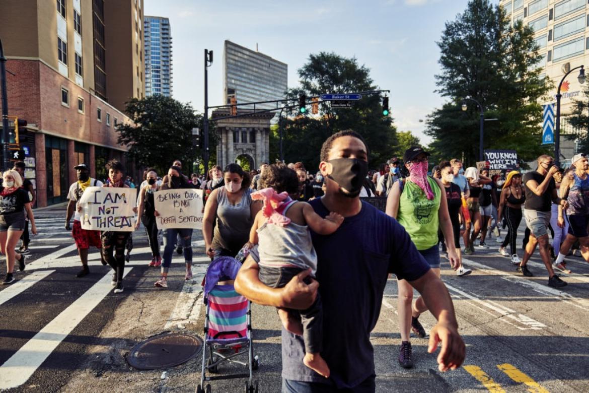 Man holds young child while marching in BLM protest