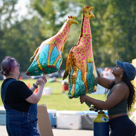 People holding giraffe balloons. 