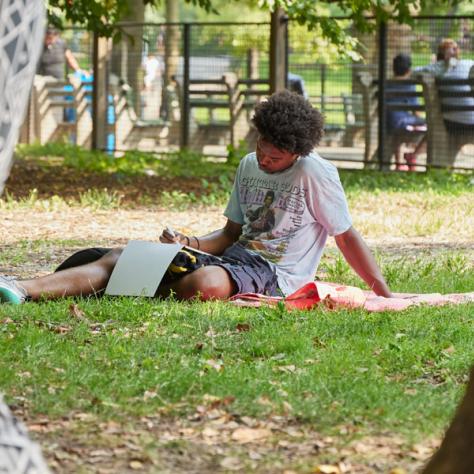 Man drawing on picnic blanket. 