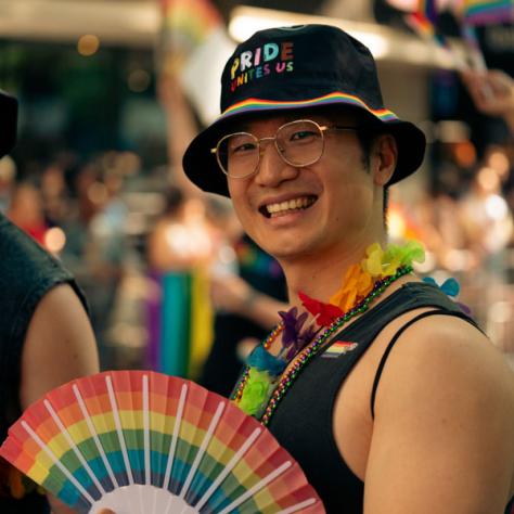 Man posing with pride fan. 