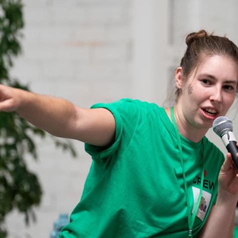 Woman pointing and talking into microphone. 