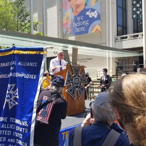 People at a rally and man on stage. 