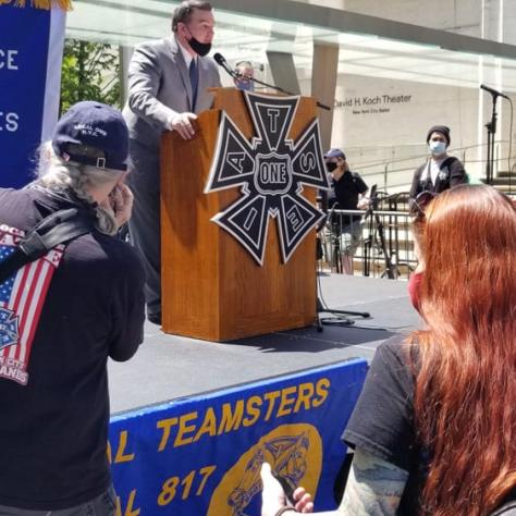Man on stage speaking at a rally. 