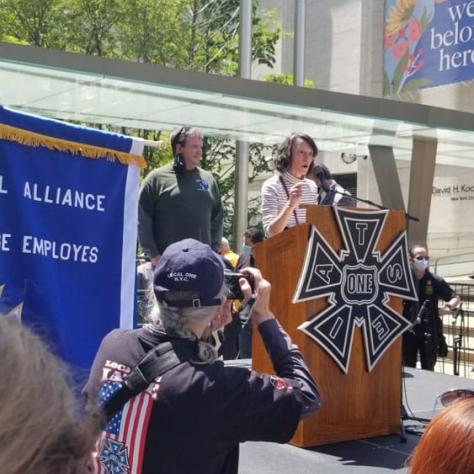 Person speaking on stage while people watch. 
