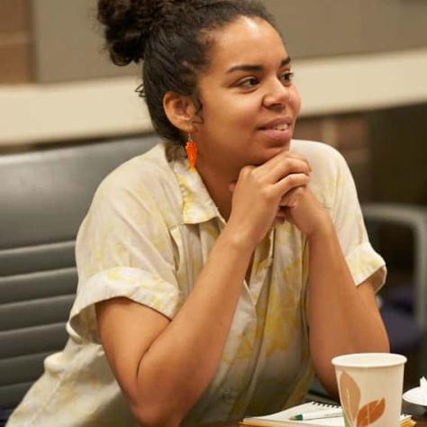 Woman sitting at table watching something. 