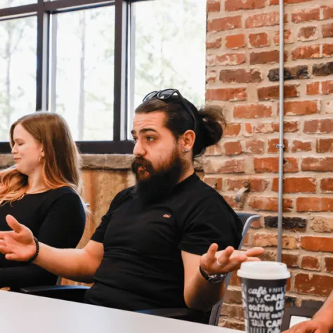 Man talking with arms out at a table. 