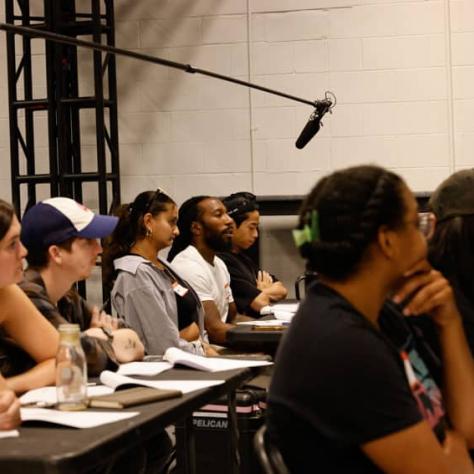 Audience sitting at tables watching something. 