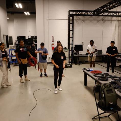 Group of people watching a person standing in the middle of a room. 