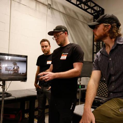 Men standing and looking at a screen. 