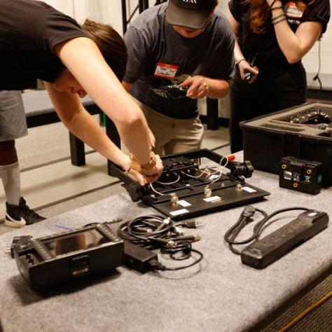 People looking at gear on a table. 