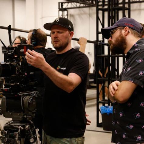 Man working behind camera while people watch. 