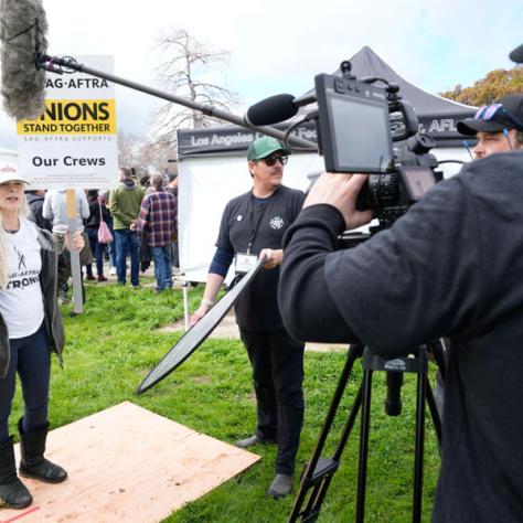 Man videoing woman at rally. 
