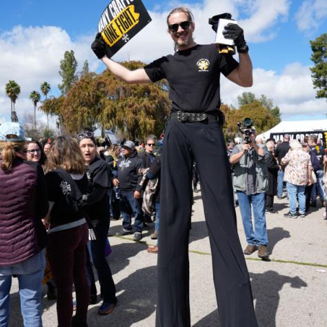 Man on stilts with rally sign. 