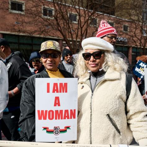 Women holding 'I am a woman' sign. 