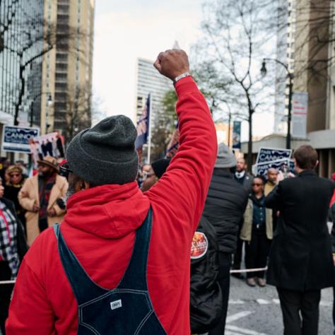 Man in red sweatshirt holding fist in air from behind. 