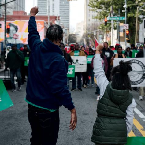 View of people holding fist in the air from behind. 