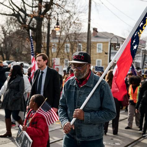 People marching with a flag at event.