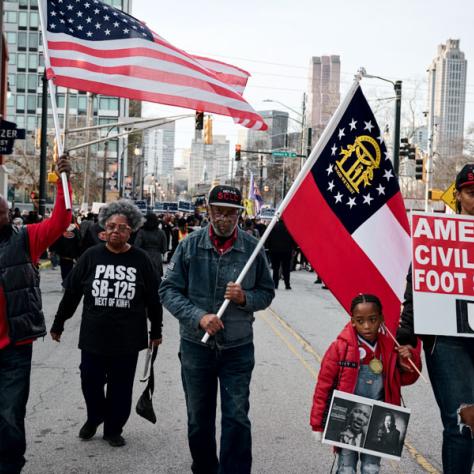 People marching with signs and flags at event.