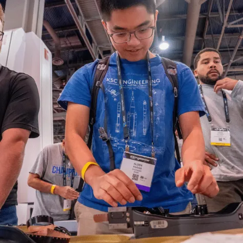 Man standing at table smiling and looking at equipment. 