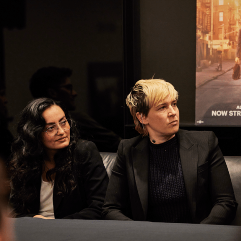 Two people sitting at a table watching something. 