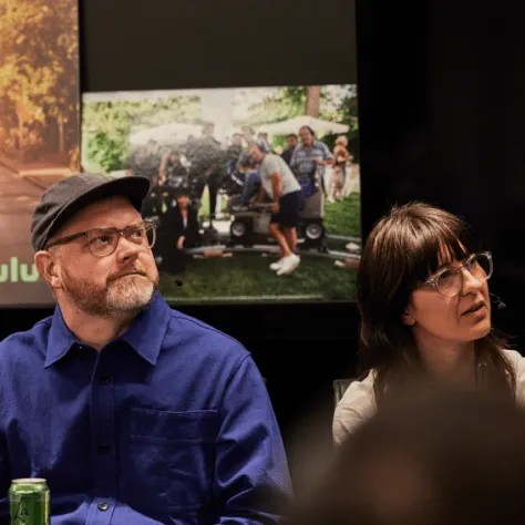 Two people sitting at a table watching something. 