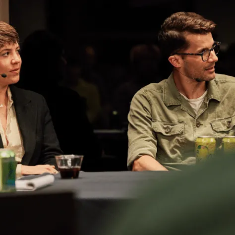 Two people sitting at table looking at something. 