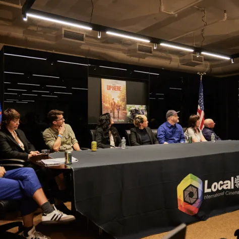 Panel of people sitting at a table at the front of the room. 