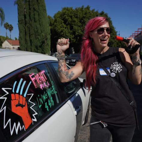Woman next to car with decorated window. 