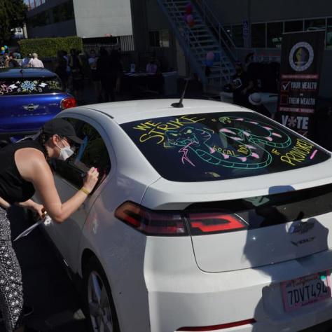 Person drawing on a car window. 