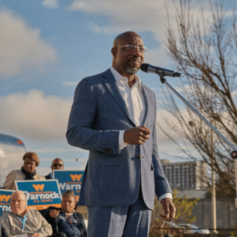 Man on stage speaking into mic. 