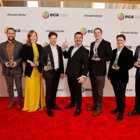 Group of award winners posing for photo with awards. 