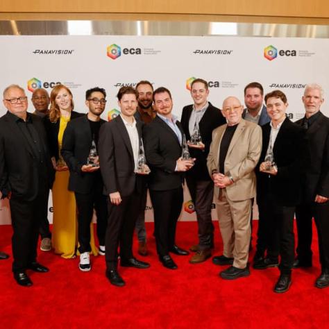 Group of award winners posing for photo with awards. 