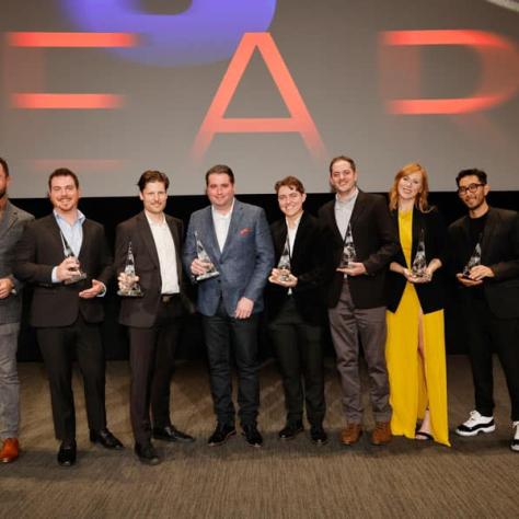 People on stage posing with awards. 