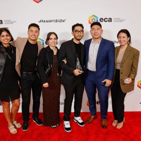 Group of people posing for photo in front of backdrop. 