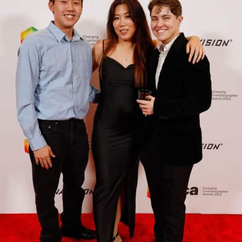 People posing for photo in front of backdrop. 