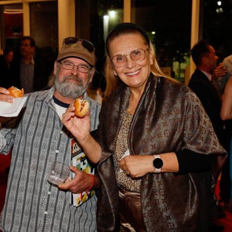 Two people posing for photo with food. 