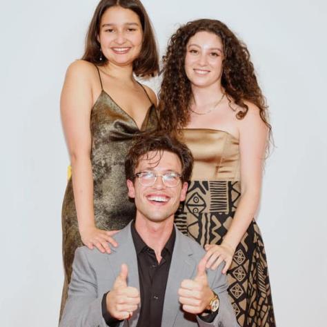 People posing for photo in front of backdrop. 