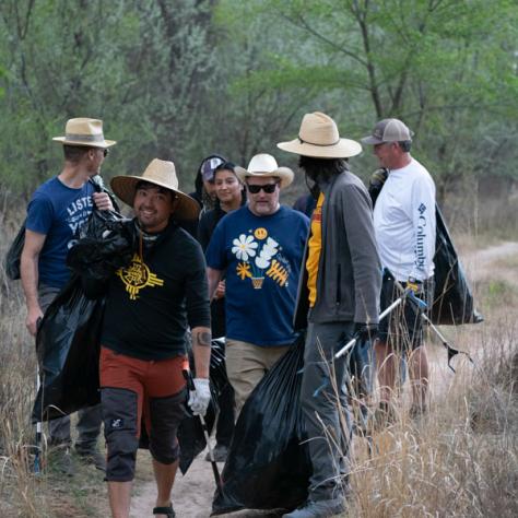 Group of people picking up trash outside. 