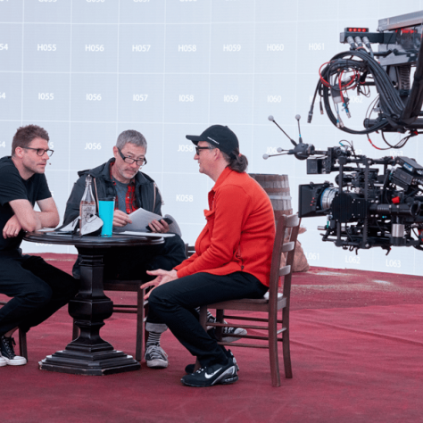 People sitting at table with camera pointing at them. 