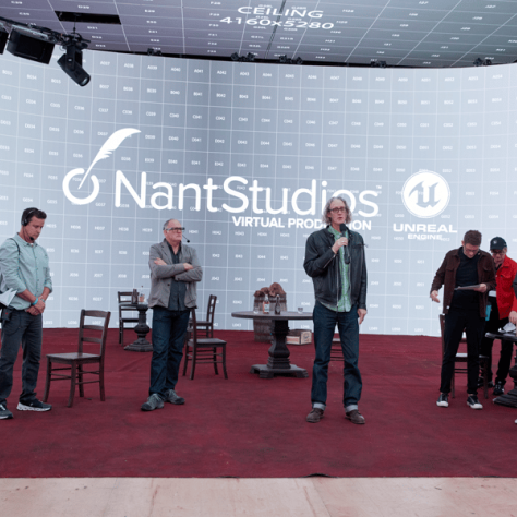 People standing on stage with backdrop. 