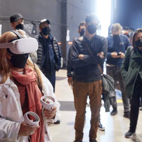 Woman playing VR set with people watching. 