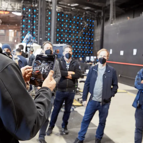 People standing and listening to someone talk with masks on. 