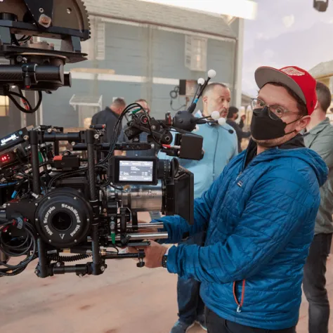 Man in blue jacket looking at a camera. 