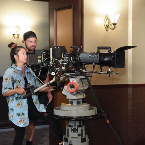 Two people working behind a camera. 