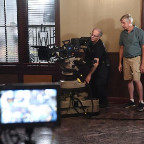 Two men working behind a camera. 