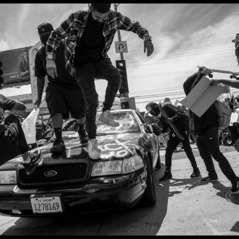 People jumping on a cop car. 