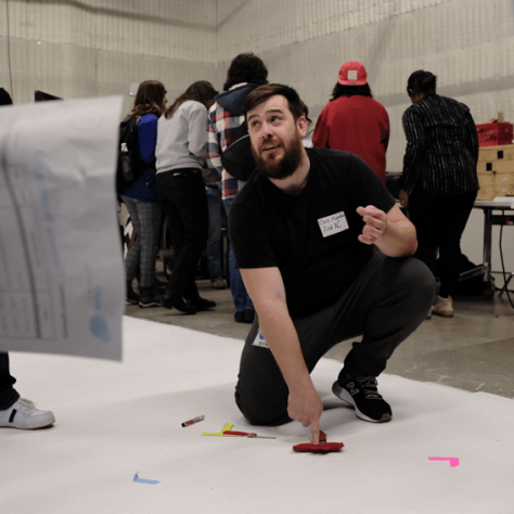 Man kneeling on the ground pointing to something. 