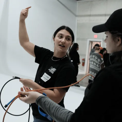 Woman talking to someone holding a cable. 