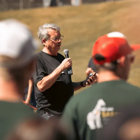 Man speaking into mic with people watching. 