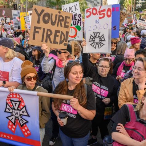 People marching while holding signs and a banner